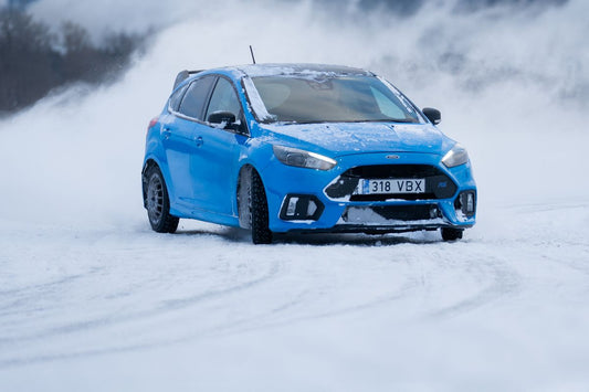 Car driving along a snow-covered road, comparing winter and all-season tires in Quebec