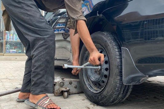 Mechanic using a lug wrench to change a tire, illustrating when to change winter tires