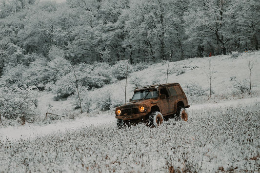 Car driving across a snowy road, comparing winter and all-weather tire performance