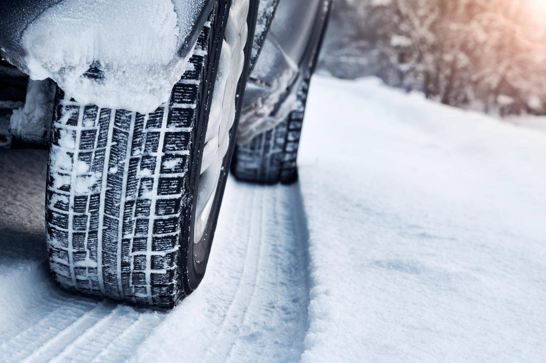 Gros plan de la bande de roulement d’un pneu d’hiver sur une route enneigée